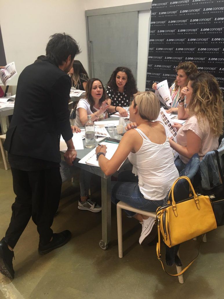 Un hombre con traje negro se dirige a un grupo de mujeres sentadas alrededor de una mesa