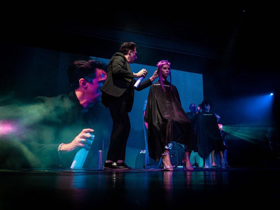 Un estilista en el escenario peina el colorido cabello de una modelo