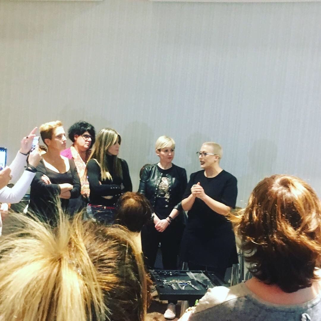 Un grupo de mujeres en el escenario, una de ellas hablando, frente a una audiencia en una sala bien iluminada.