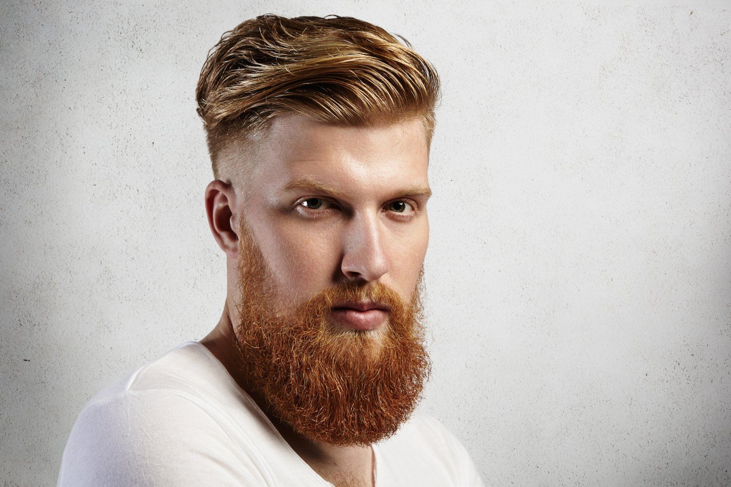 Hombre de pelo y barba rojos, piel clara, mirando directamente al espectador.