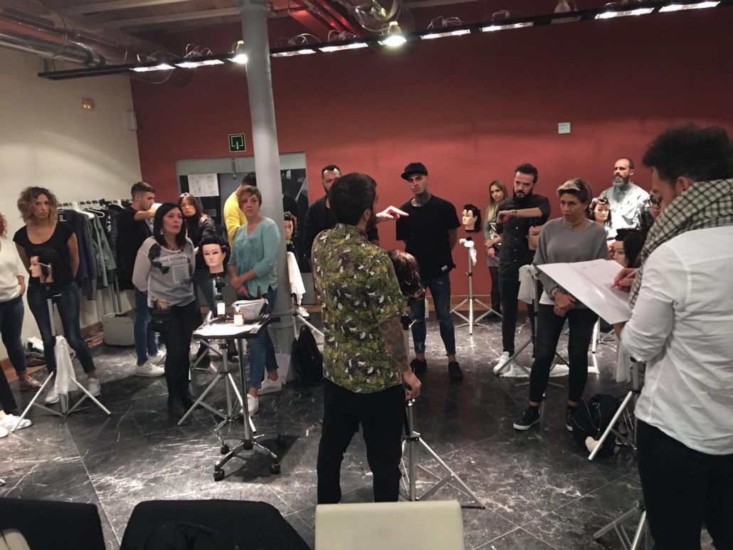 Un grupo de personas observa a un peluquero demostrar técnicas en un estudio.