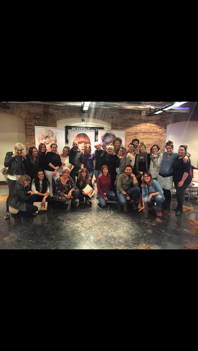 Un grupo de personas posa juntas en un estudio. Sonríen, de pie frente a una pared de ladrillo.