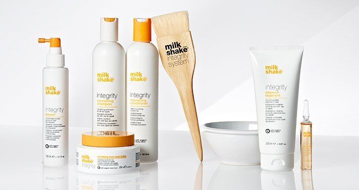 Productos para el cabello Milk Shake sobre un fondo blanco: champú, acondicionador, tratamiento, cepillo, recipiente y suero.