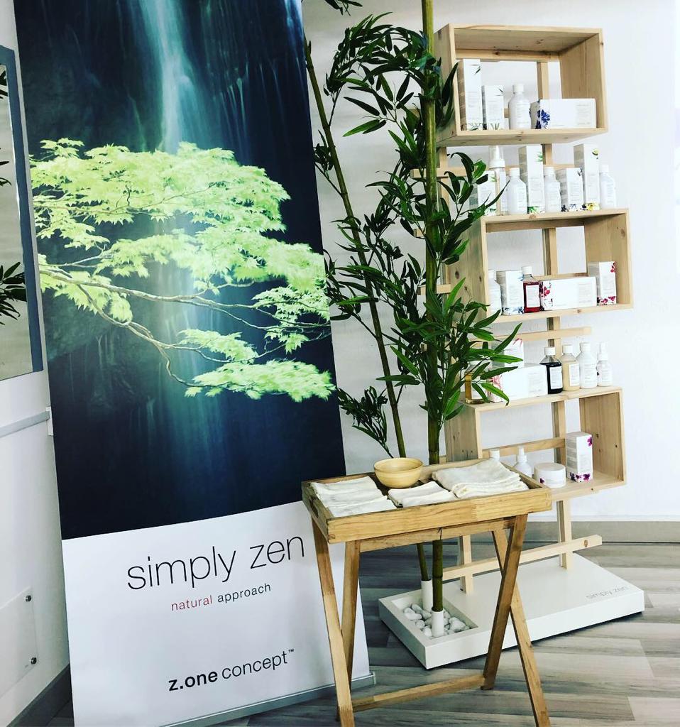Expositor de productos “simplemente zen”: pancarta, estanterías con productos, bambú y una pequeña mesa de madera.