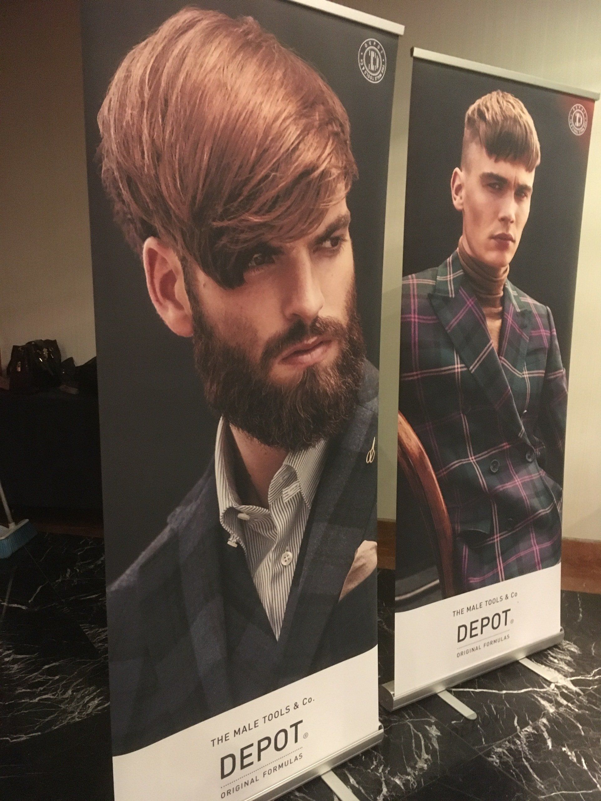 Dos pancartas publicitarias de DEPOT que muestran hombres con cortes de pelo elegantes y trajes a cuadros.