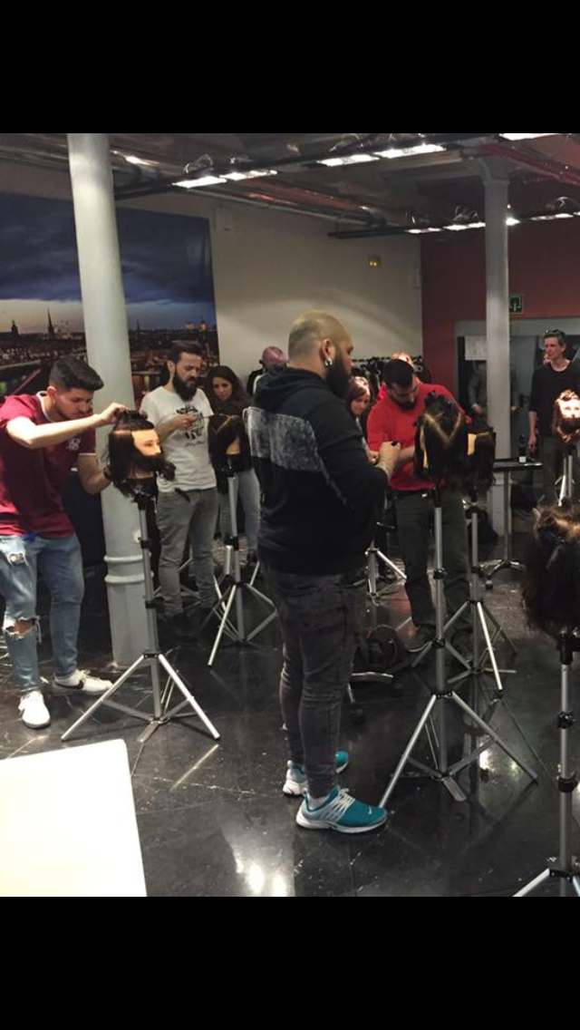 Grupo de personas en un estudio, algunas filmando. Un hombre con barba está en el centro, con chaqueta negra.