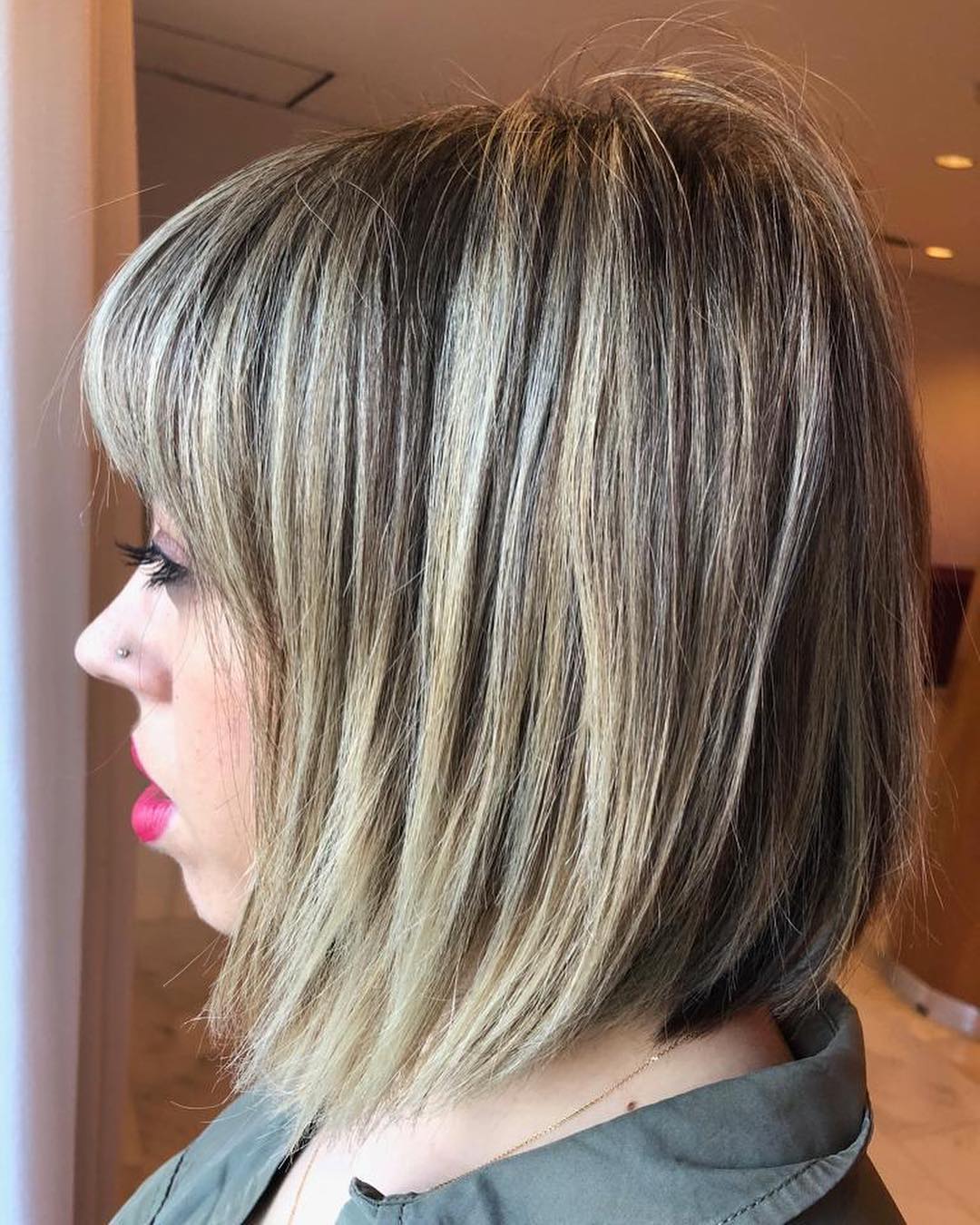 Mujer con corte de pelo bob en ángulo y flequillo, cabello castaño claro con reflejos rubios.
