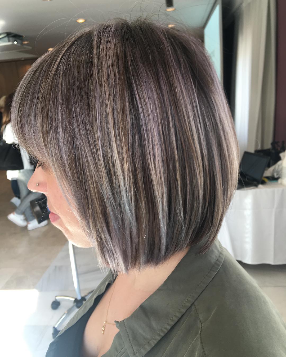 Mujer con un corte de pelo bob corto en capas con tonos grises, marrones y rubios.