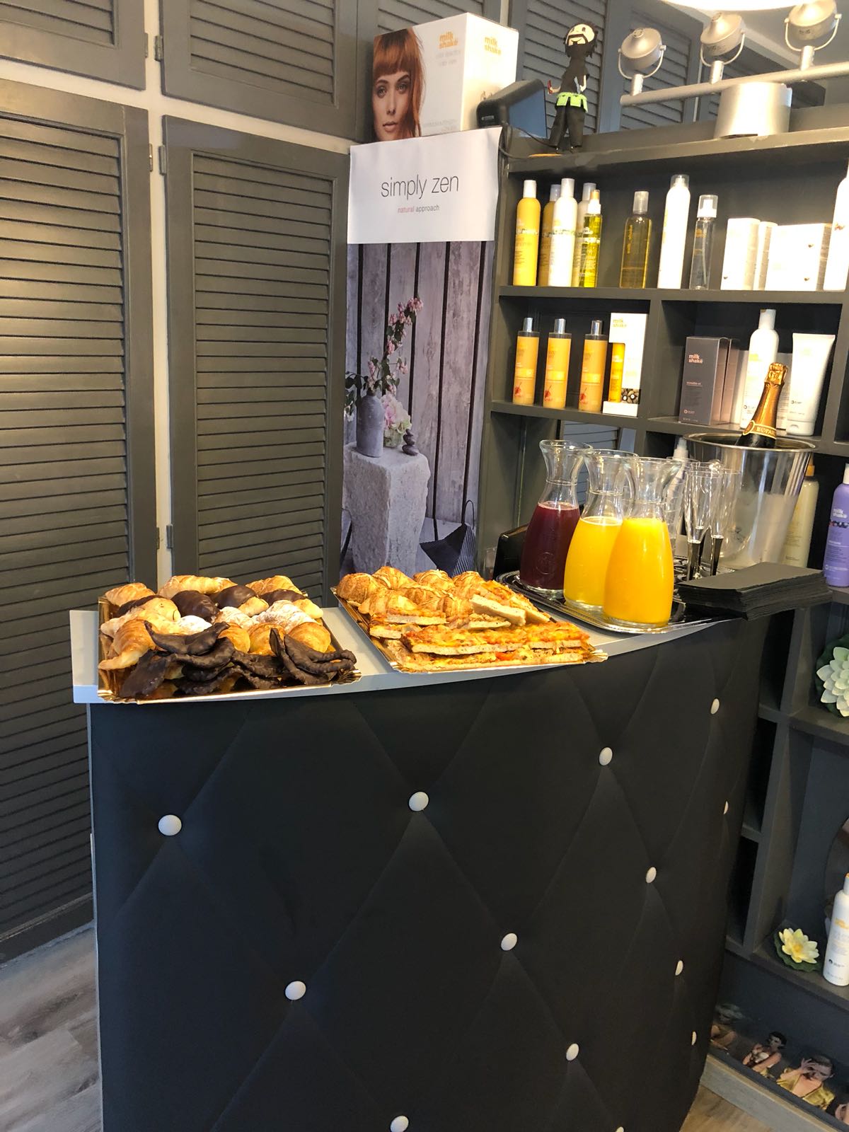 Mostrador de salón con pasteles, bebidas y productos para el cabello.
