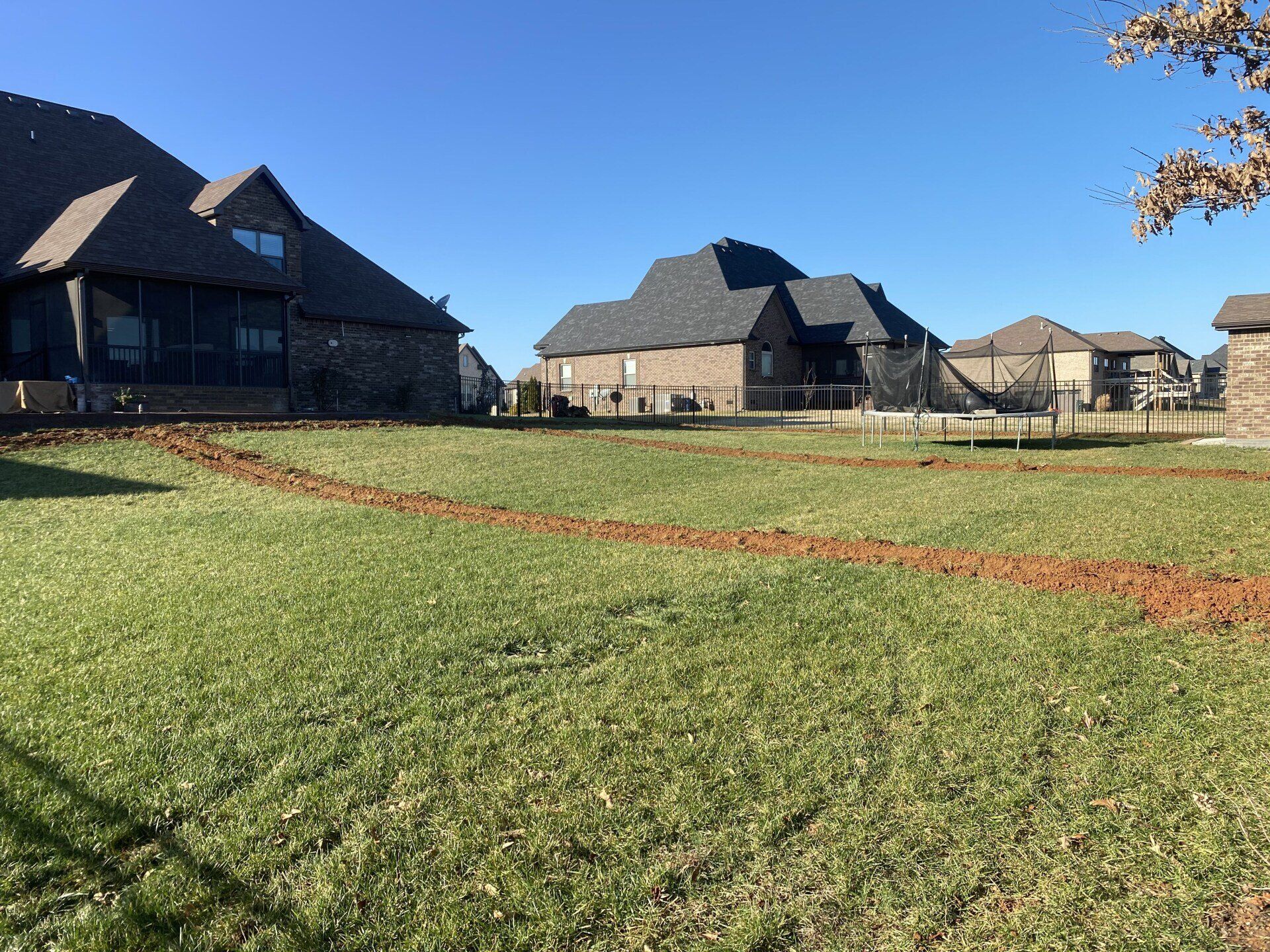 Suburban houses behind a grassy field under a clear blue sky