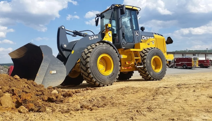 Excavation A yellow and black wheel loader is driving through a dirt field.