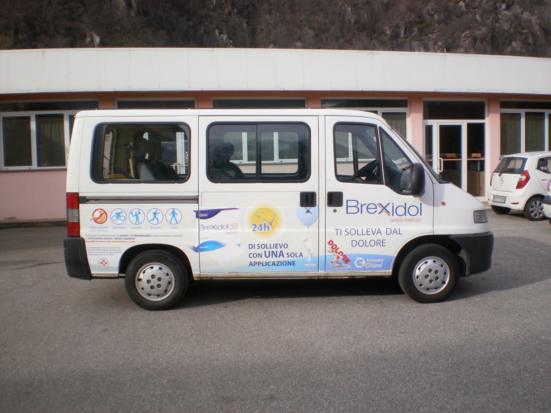 Un furgone commerciale bianco parcheggiato davanti a un edificio, con il marchio