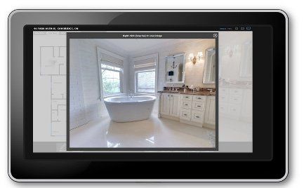 Tablet displaying a bathroom with a white freestanding tub, vanity, and windows.