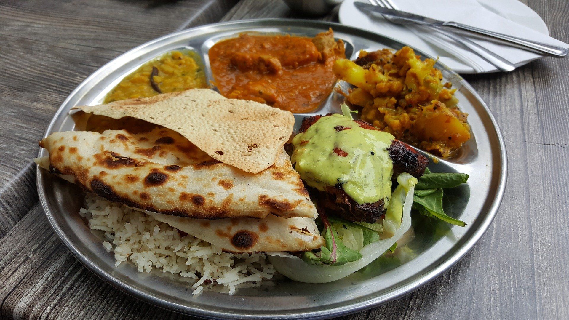 A plate of food with rice , bread , and vegetables on a table.