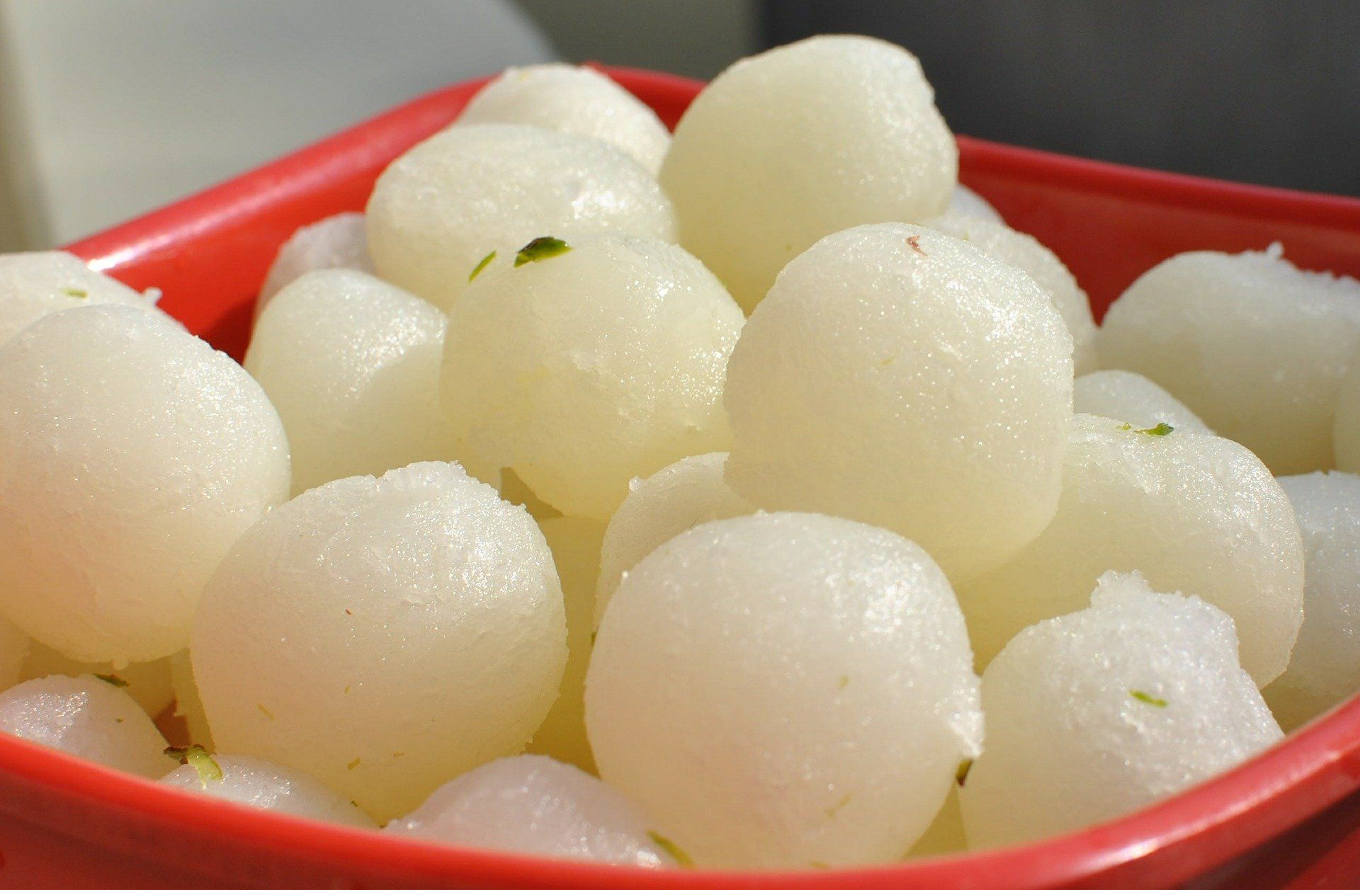 A red bowl filled with white balls on a table.