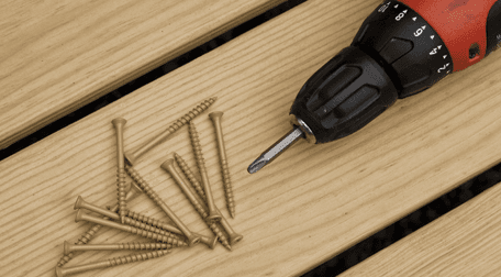 A drill and screws on a decking plank