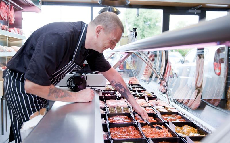 person checking food in refrigeration tubs