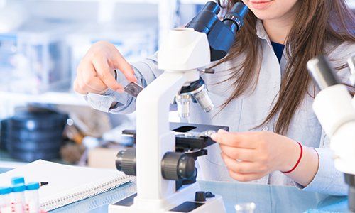 una donna mentre usa un microscopio