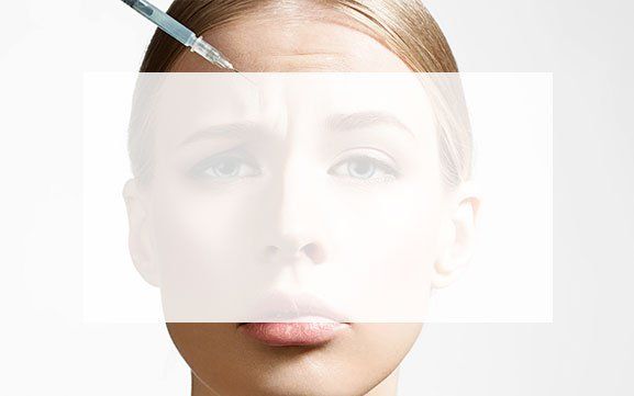 A woman is getting a botox injection in her forehead.