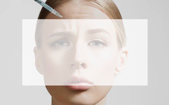 A woman is getting a botox injection in her forehead.