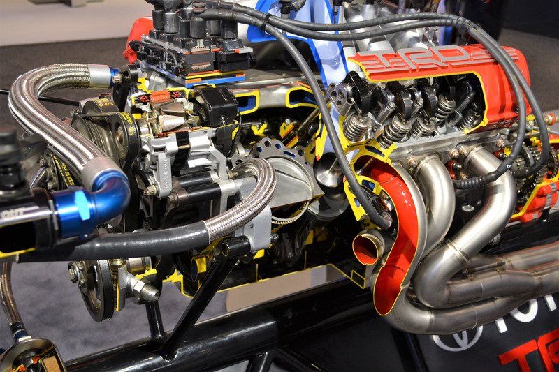 A cross-section of a Toyota TRD engine, revealing internal components, exhaust headers, and wiring in a display setting.