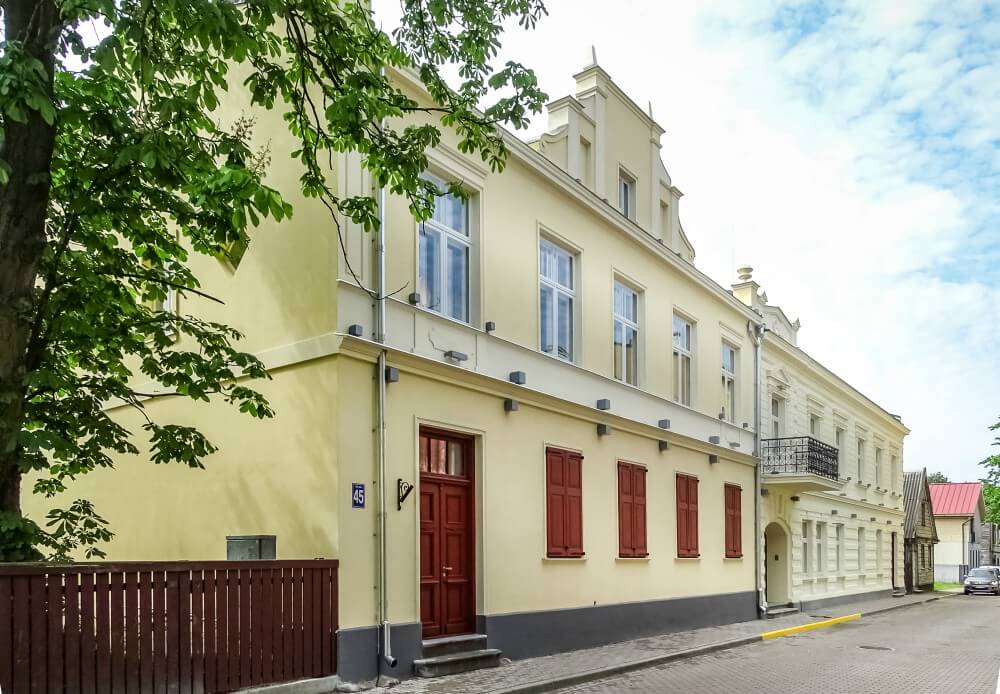 Каменный дом с желтой отделкой и красными дверями