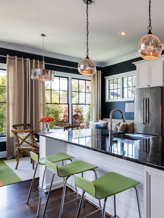 The nice modern kitchen with a partial view of the seating area with the lights on