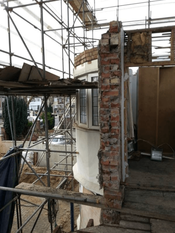 House with the side wall removed and scaffolding outside