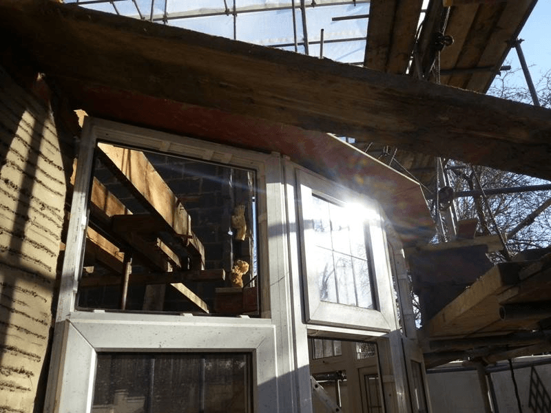 Sun shining on a window with scaffolding where a roof is being built