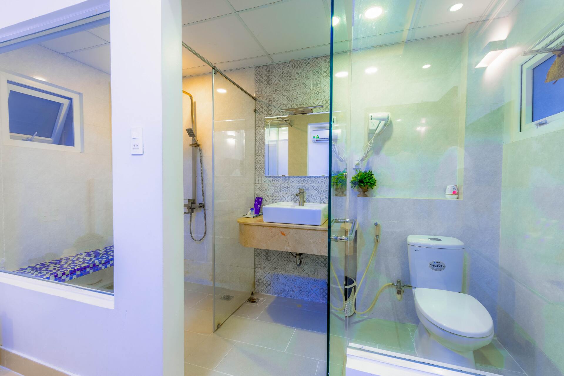 A bathroom with a toilet , sink and shower.