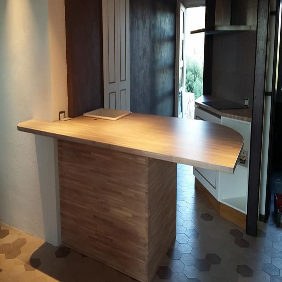 Isola da cucina in legno con piano di lavoro inclinato in un interno domestico moderno.