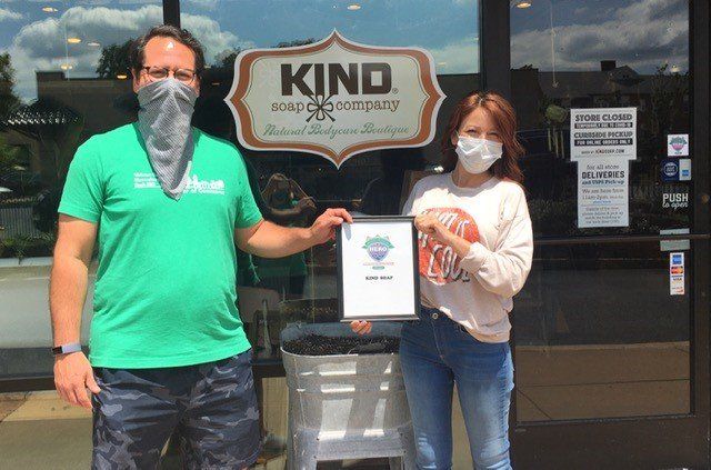 Two people holding a framed certificate in front of a 