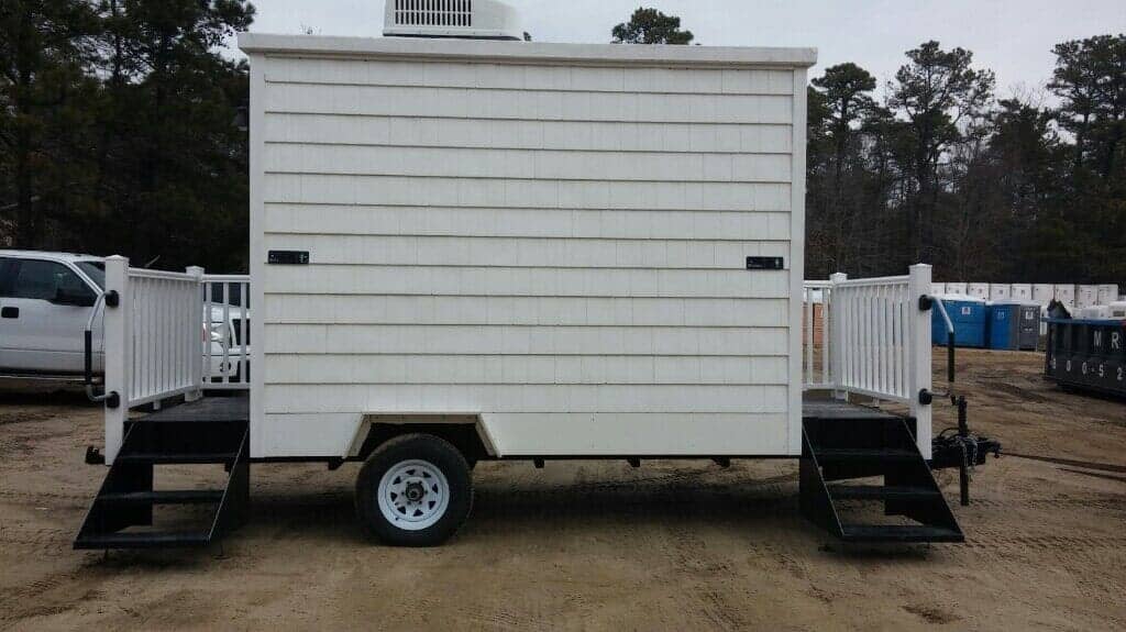 White trailer with a platform and steps on both sides. Located outdoors.