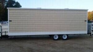 Enclosed cargo trailer with tan siding and white trim. It has two wheels.