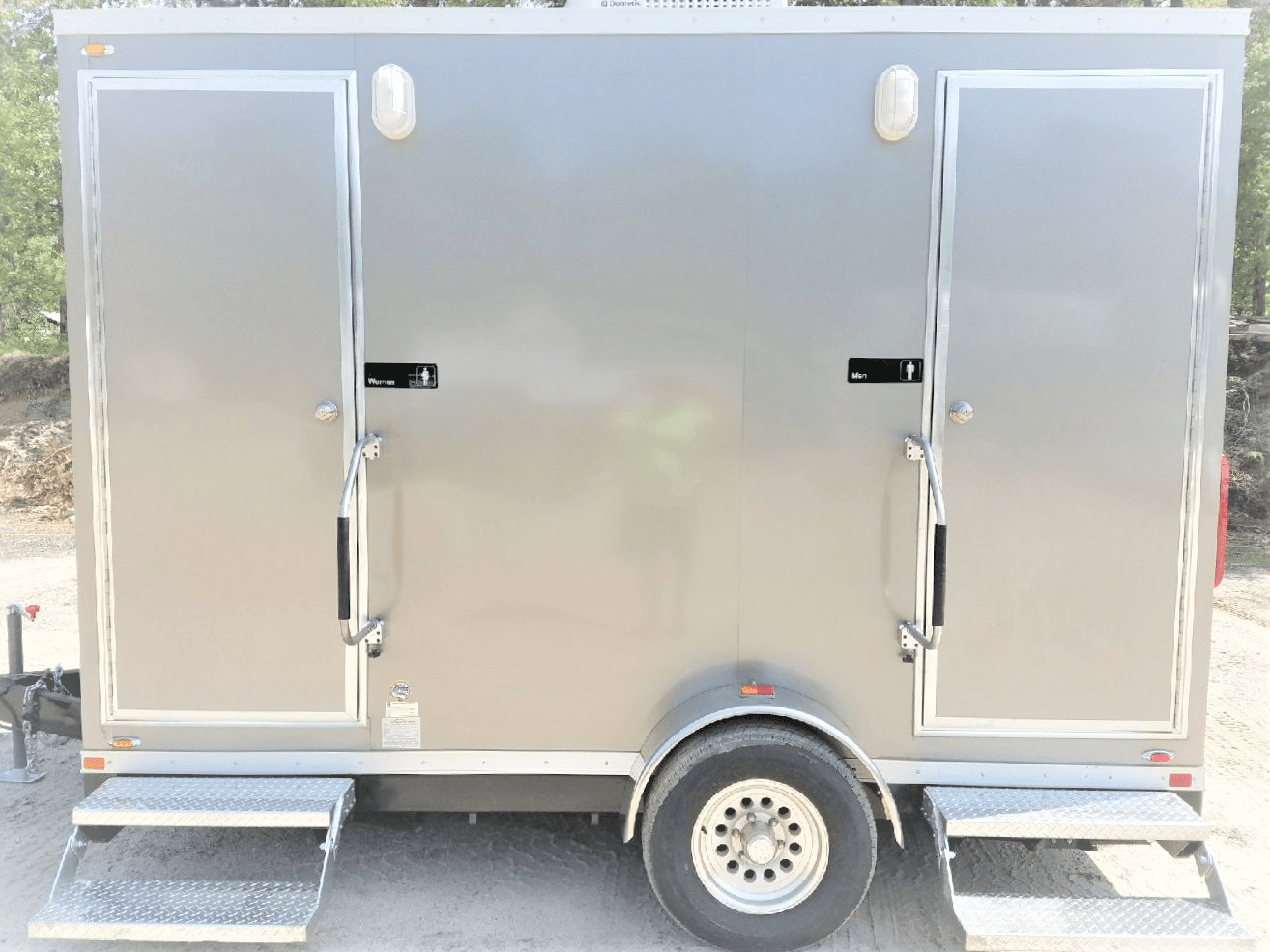 Gray portable restroom trailer with two separate doors and built-in steps.