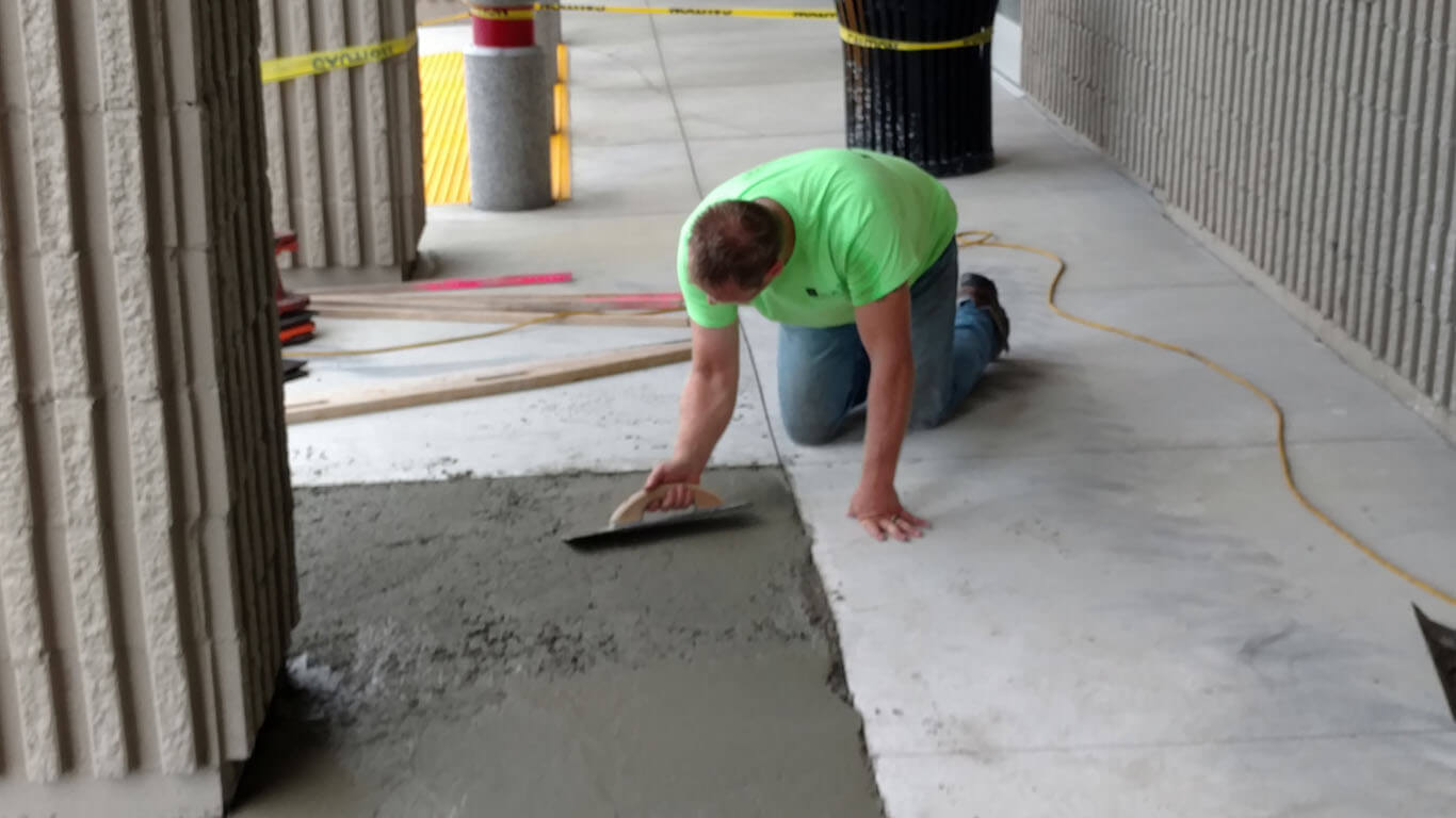 Concrete Repair Services. A technician leveling concrete on a commercial walk.