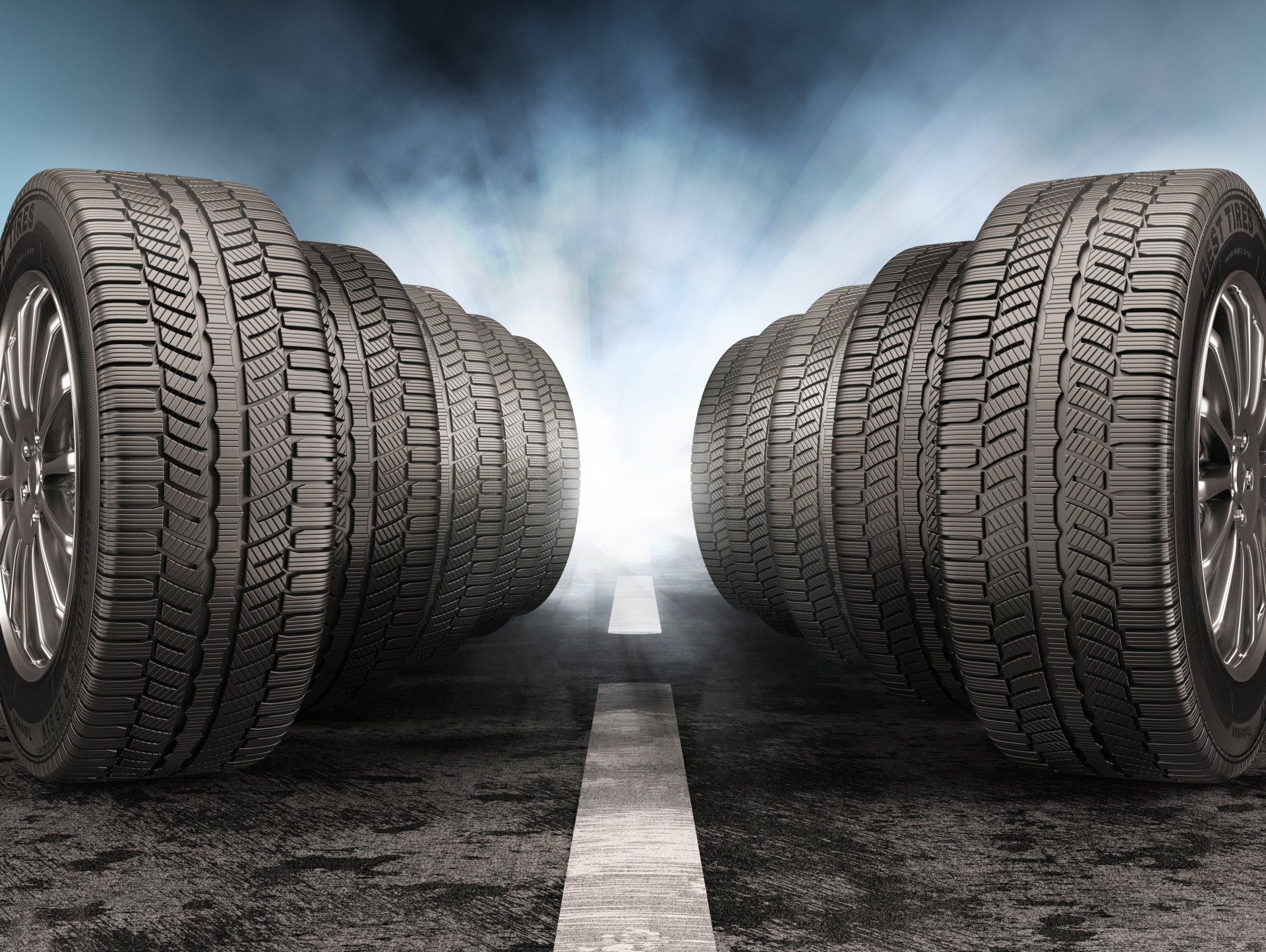 A row of tires are stacked on top of each other on the side of a road.