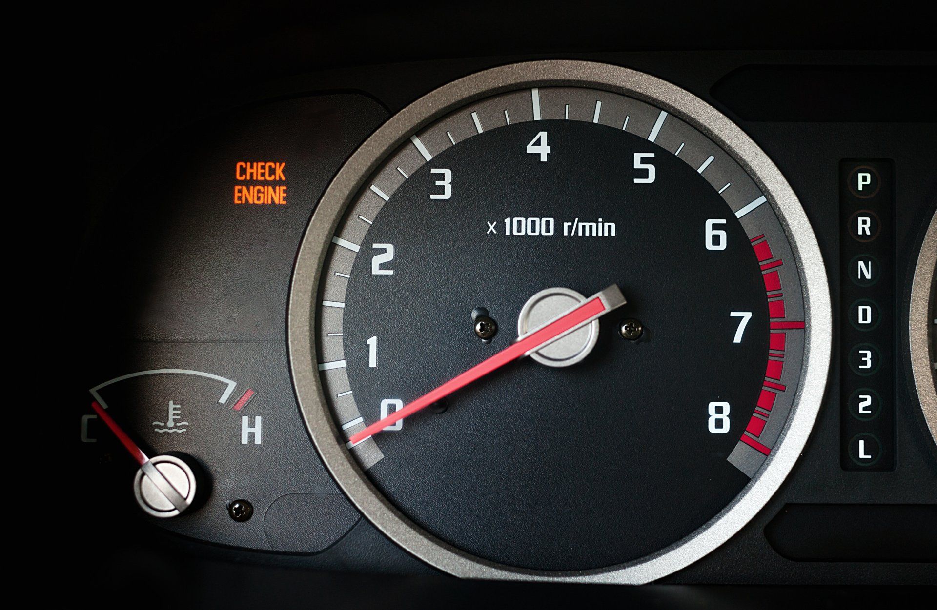 A close up of a car dashboard with a check engine light on