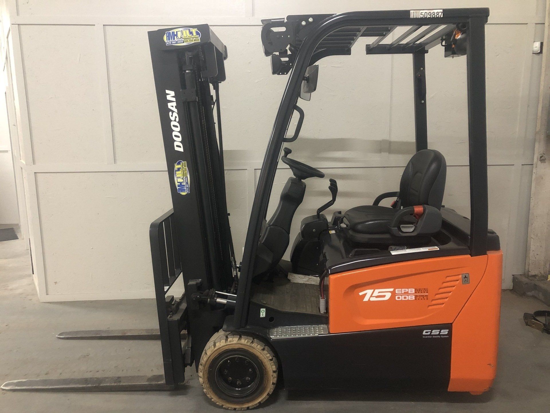 Orange forklift parked indoors against a white wall