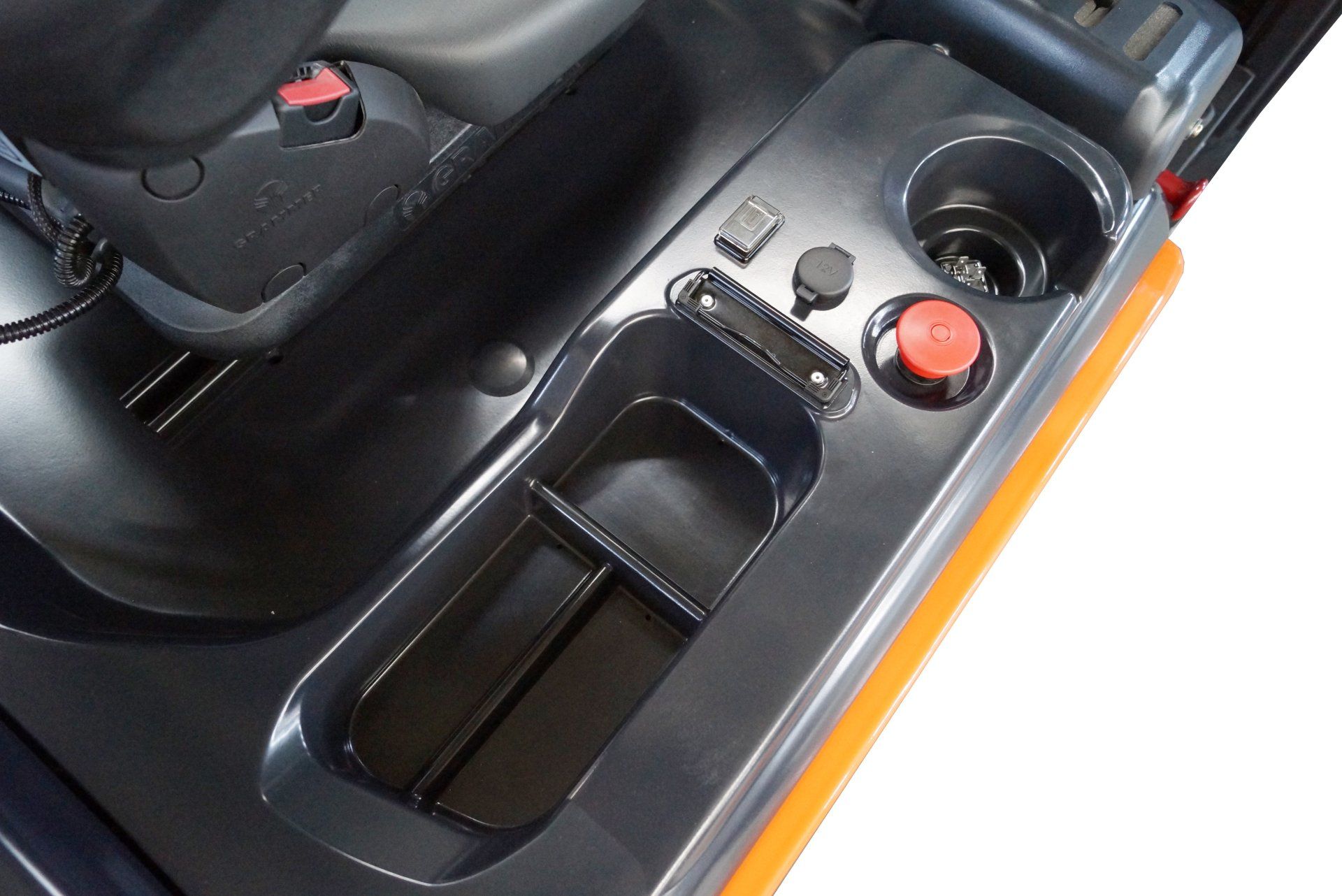 Close-up of a car console with cup holders, storage tray, and orange button on black trim