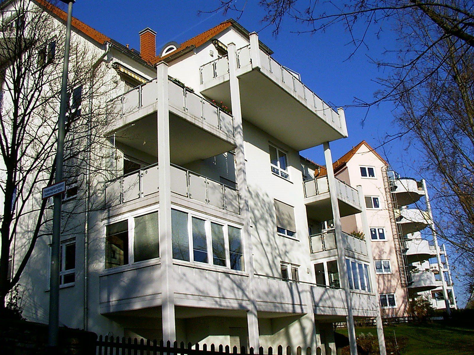Ein großes weißes Gebäude mit Balkonen und einem roten Dach