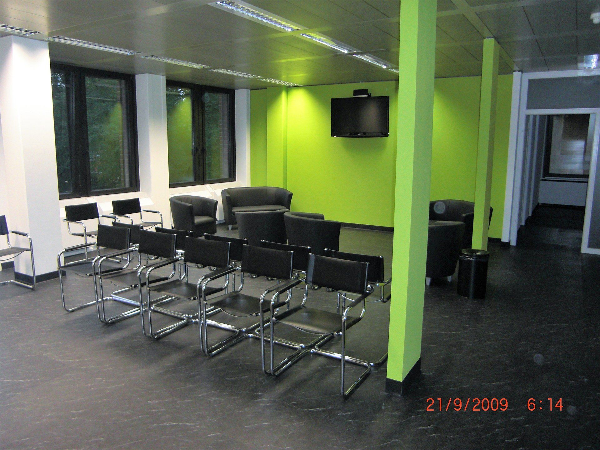 Ein Wartezimmer mit Stühlen und einem Fernseher an der Wand