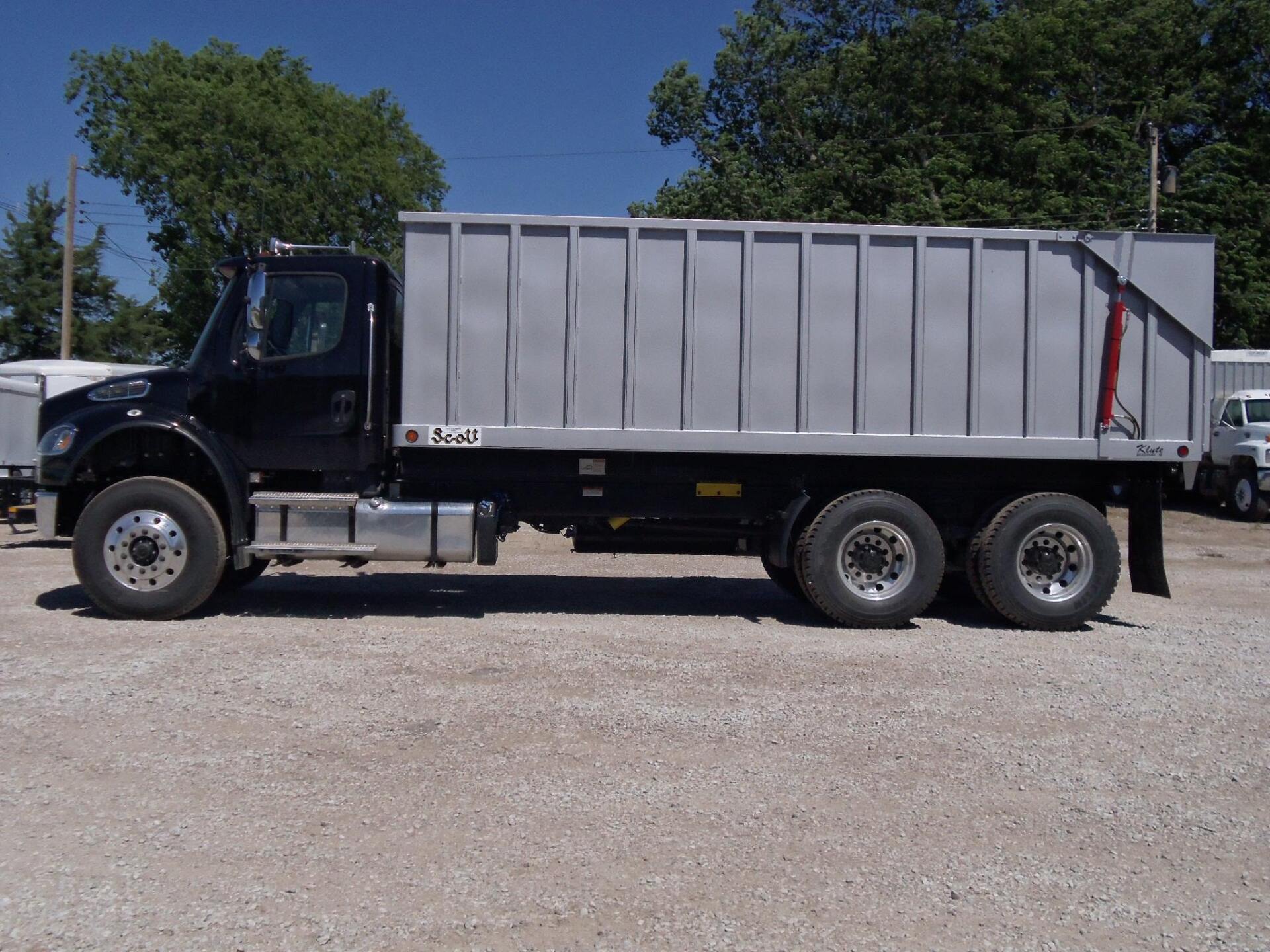 A dump truck is parked in a gravel lot