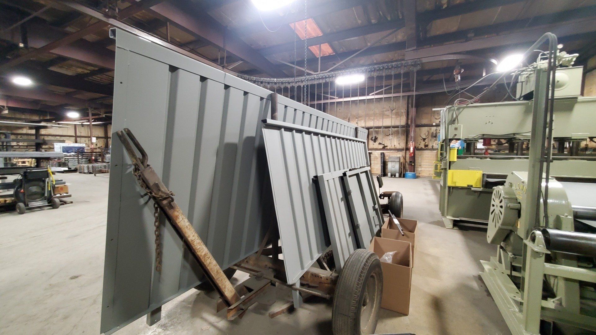A trailer is sitting in a warehouse next to a machine.