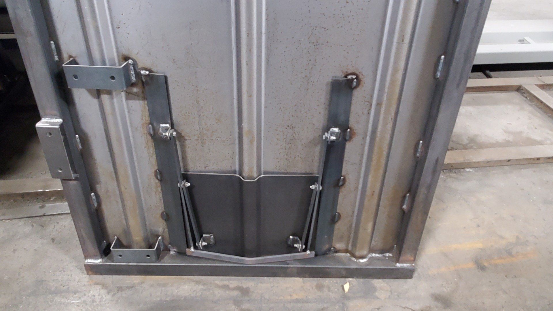 A metal door is sitting on a concrete floor in a warehouse.