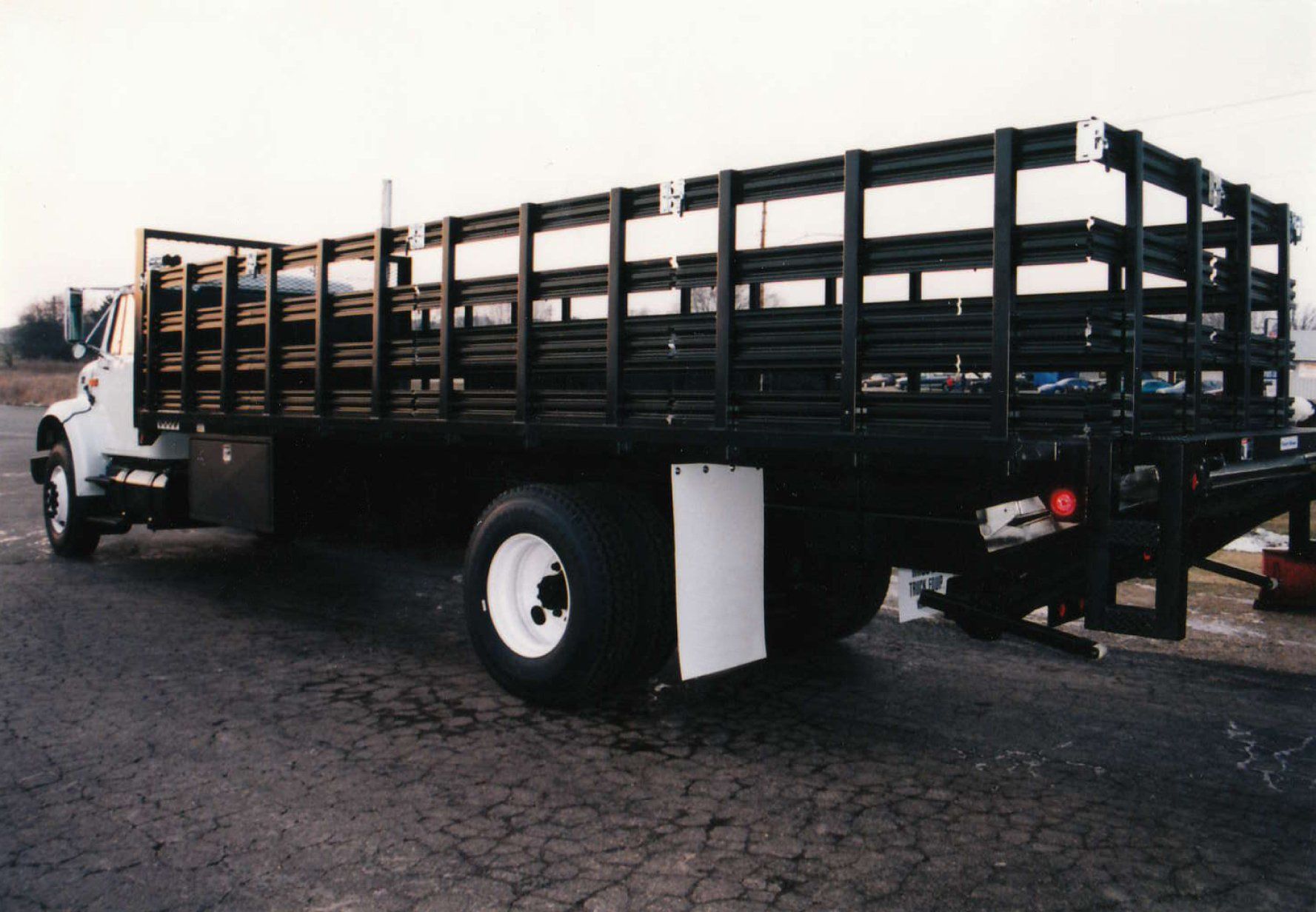 A truck with a wooden bed is parked on the side of the road