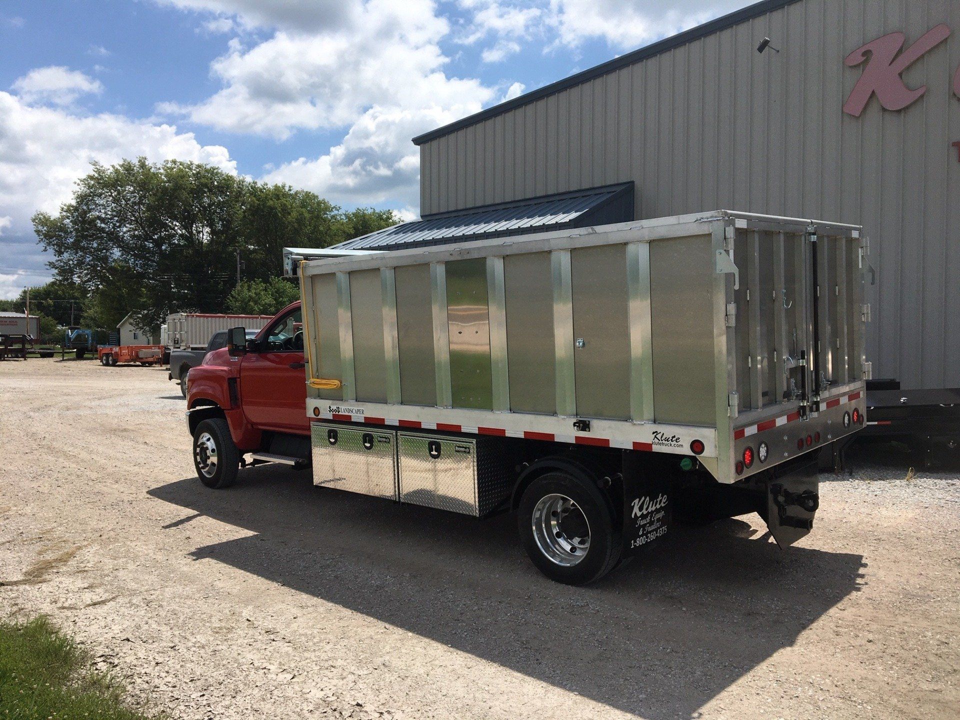 A red dump truck is parked in front of a building.