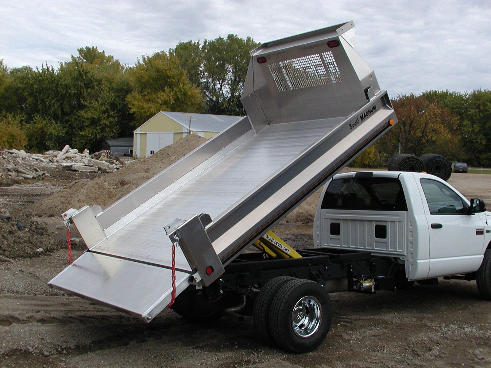 A white dump truck is parked on a dirt road