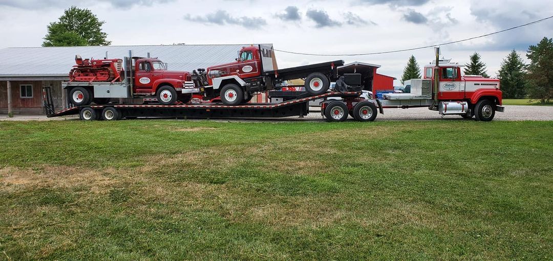 A semi truck is carrying two fire trucks on a trailer.