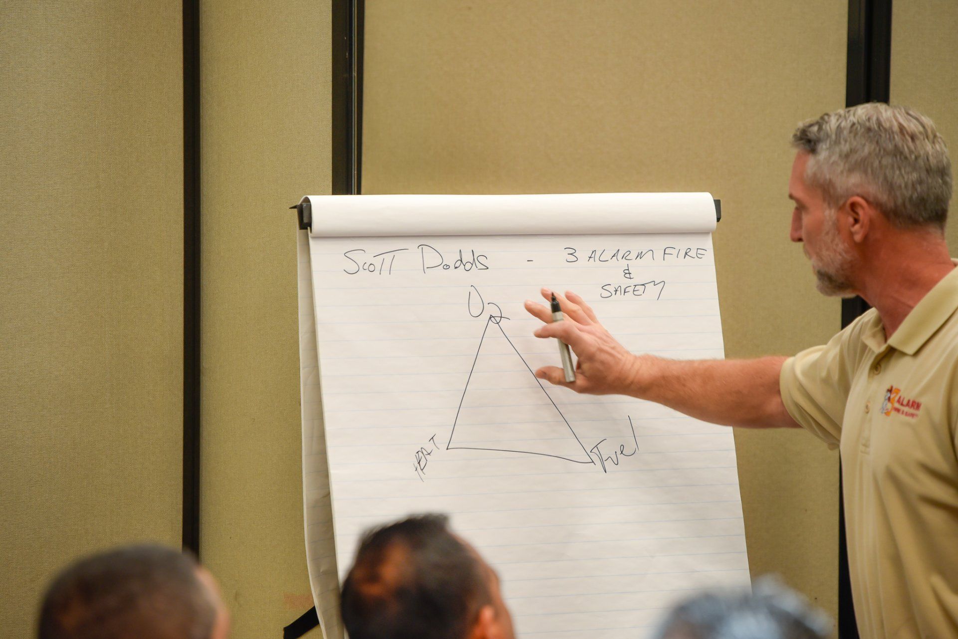 Speaker points to chart on flip pad during presentation in a conference room